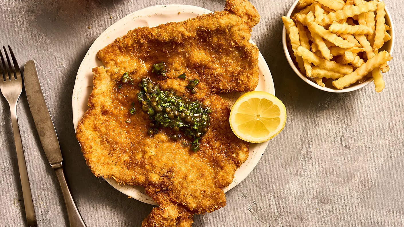 Paneroitu possunleike kapriksilla ja sitruunalla. Ohessa ranskalaiset peruna.