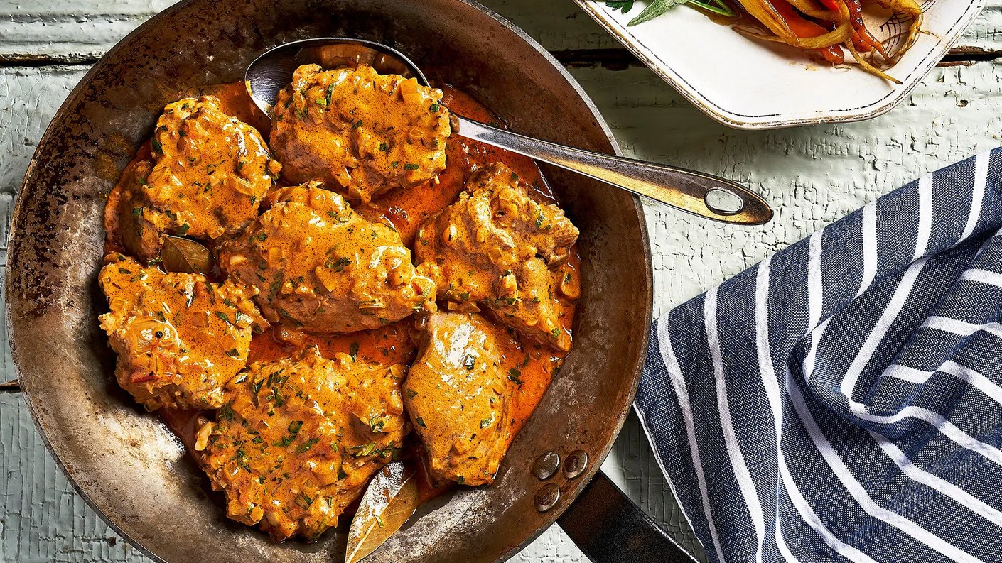 Paistinpannulla paistettuja kalkkunanpaloja ruskeassa kastikkeessa. Vieressä sinivalkoraidallinen keittiöpyyhe.