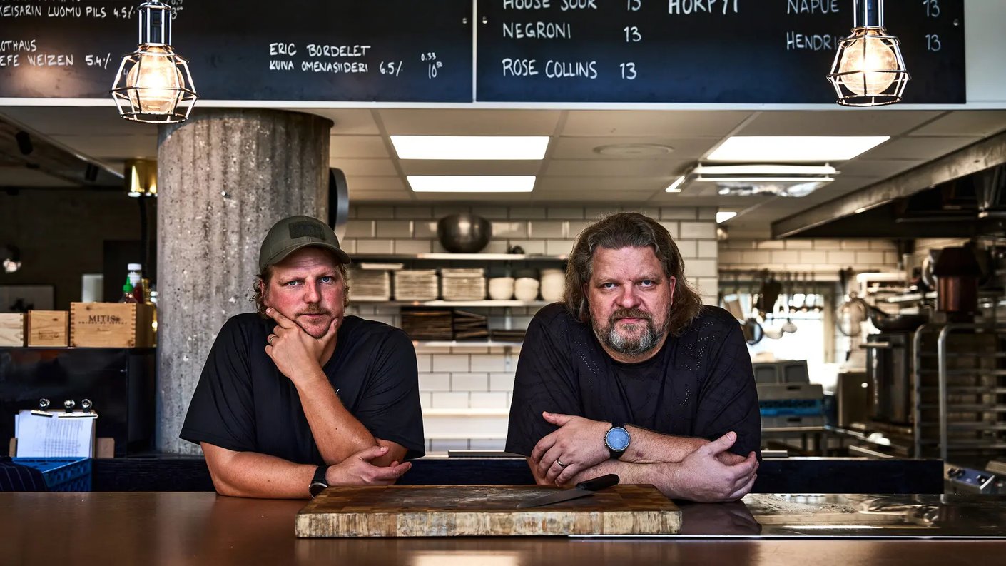 Veljekset Pontevan Mika Roito ja Pekka Salmela nojaavat tiskin takana ja katsovat kameraan. Edessä teräksisellä tasolla on puinen leikkuulauta ja lihaveitsi. Taustalla näkyy ravintolakeittiö, juomahinnasto ja kaksi metallilankaista lamppua.